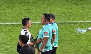 Achmad Resal sedang berdiskusi di pinggir lapangan hijau bersama staf pelatih lainnya.