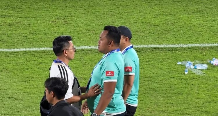Achmad Resal sedang berdiskusi di pinggir lapangan hijau bersama staf pelatih lainnya.