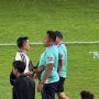 Achmad Resal sedang berdiskusi di pinggir lapangan hijau bersama staf pelatih lainnya.