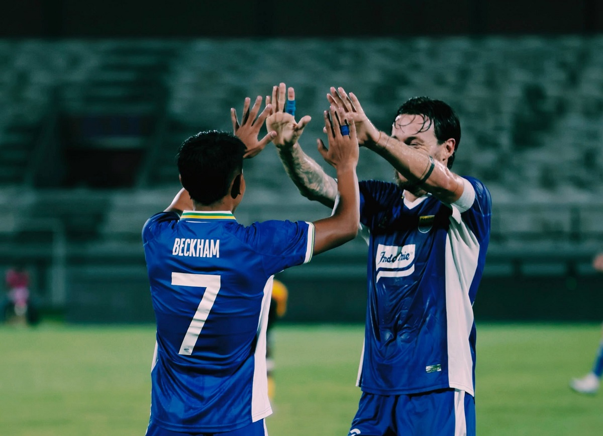 Dua pemain Persib Bandung, Beckham Putra bernomor punggung 7 dan rekannya, melakukan selebrasi tos tangan bersama di lapangan.