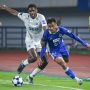 Saddil Ramdani menggunakan jersey biru saat menggiring bola di bawah tekanan pemain lawan di lapangan hijau.