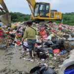 Pekerja memilah tumpukan sampah bersama alat berat ekskavator di tempat pengelolaan sampah, mendukung rencana pembangunan TPST Balikpapan pada 2027.