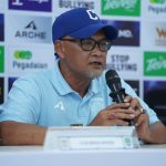 persiba-balikpapan-cari-pengganti-pelatih-sudirman.webp Pelatih Sudirman mengenakan topi dan kacamata saat memberikan keterangan dalam sesi konferensi pers Persiba Balikpapan.