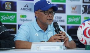 Pelatih Sudirman mengenakan topi dan kacamata saat memberikan keterangan dalam sesi konferensi pers Persiba Balikpapan.