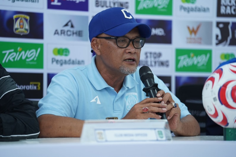 Pelatih Sudirman mengenakan topi dan kacamata saat memberikan keterangan dalam sesi konferensi pers Persiba Balikpapan.