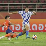 persib-bandung-tumbangkan-port-fc-thailand.webp Pemain Persib Bandung melewati tekel pemain Port FC dalam pertandingan di Thailand.