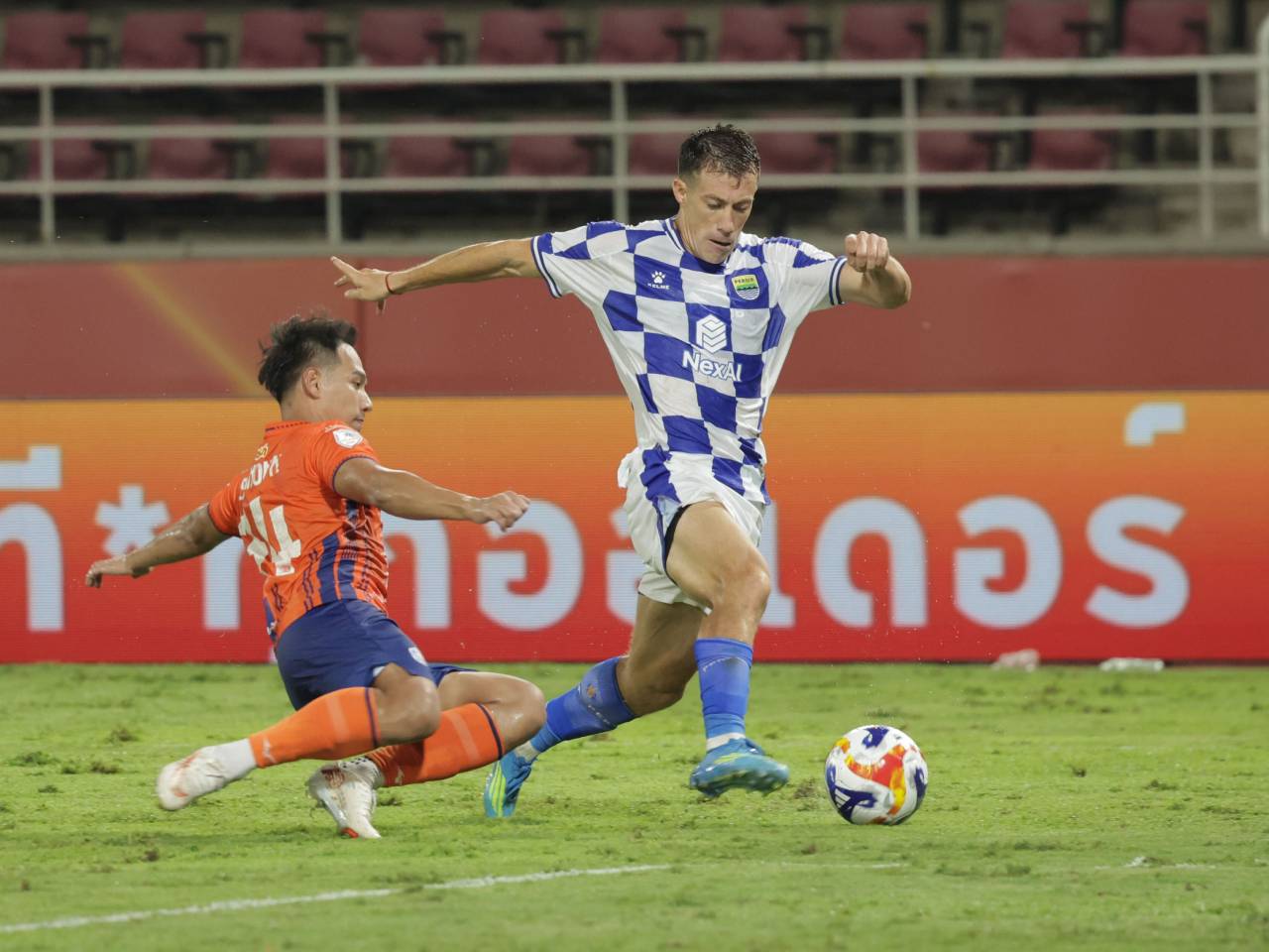 Pemain Persib Bandung melewati tekel pemain Port FC dalam pertandingan di Thailand.