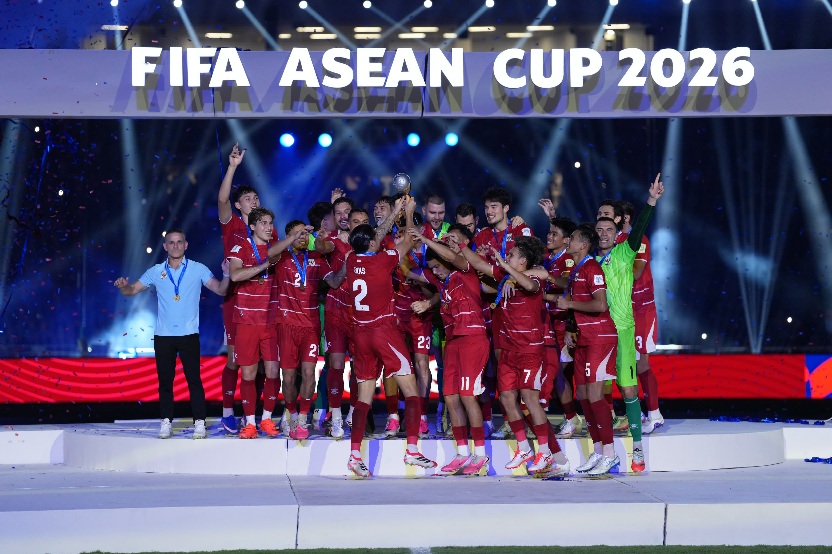 Momen Timnas Indonesia saat mengangkat trofi juara FIFA ASEAN Cup 2026 di atas podium, dengan latar belakang spanduk bertuliskan "FIFA ASEAN Cup 2026".