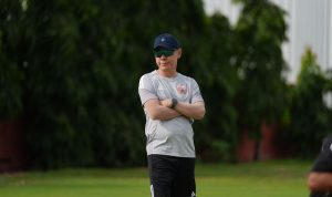 Shin Tae-yong bersedekap mengenakan topi dan kacamata hitam di lapangan latihan Persija Jakarta.