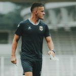 strategi-john-herdman-adu-penalti-indonesia-vs-thailand.webp Pelatih John Herdman memegang peluit dan kertas catatan strategi saat mendampingi sesi latihan Timnas Indonesia.