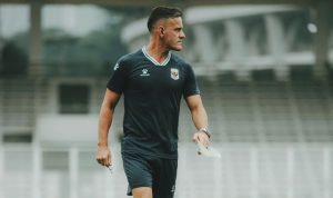 Pelatih John Herdman memegang peluit dan kertas catatan strategi saat mendampingi sesi latihan Timnas Indonesia.