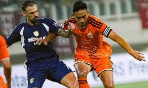 Pemain Persija Jakarta berjersey oranye berebut bola dengan lawan dalam pertandingan Super League