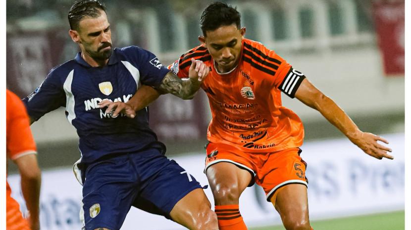 Pemain Persija Jakarta berjersey oranye berebut bola dengan lawan dalam pertandingan Super League